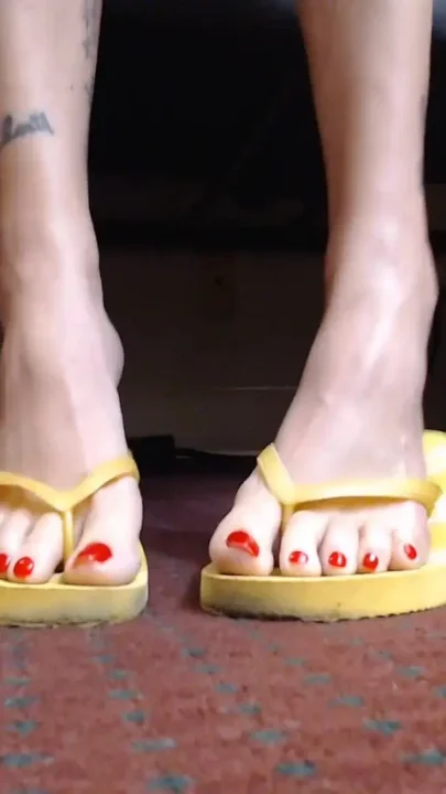 Red toenail wiggling yellow flipflops