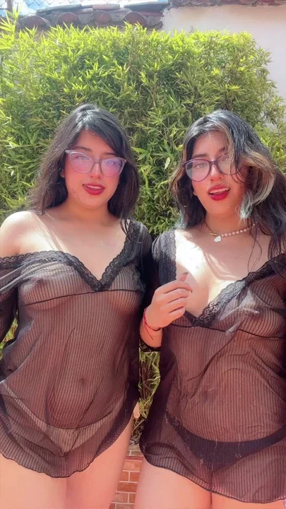 Twin sisters playing with water hose in the back yard